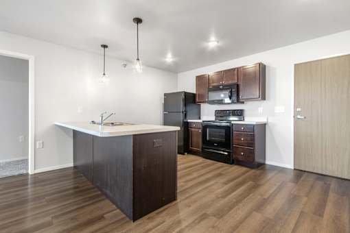 A kitchen with dark wood floors and a white island.