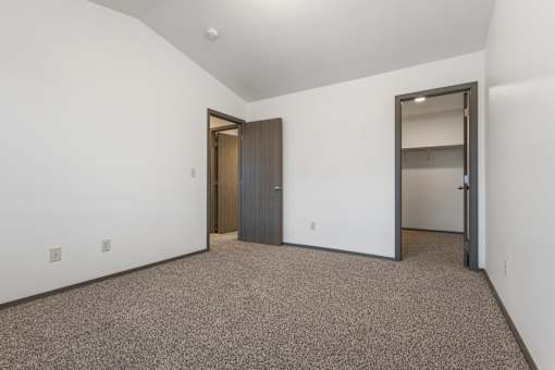 A room with a carpeted floor and a door on the left.