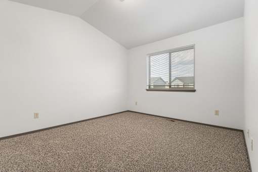 A room with a window and carpeted floor.