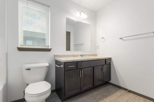 A bathroom with a white toilet, a sink with a counter, and a mirror.