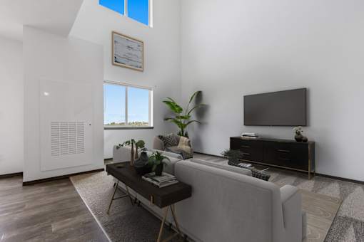 A living room with a grey couch, a coffee table, and a flat screen TV.