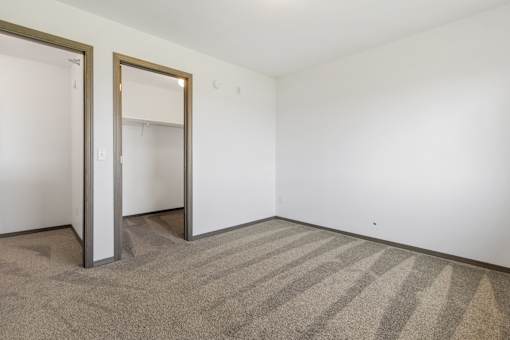 A room with a striped carpet and two open doors.