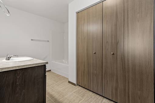 A bathroom with a sink, a shower, and a wooden cabinet.