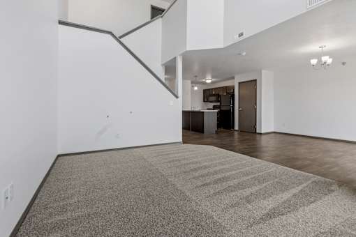 A room with a carpeted floor and a staircase.