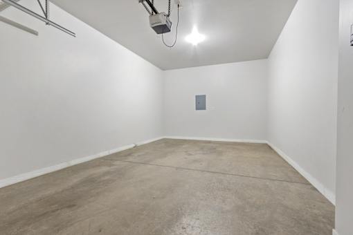 A room with a concrete floor and a white wall with a small square object on it.