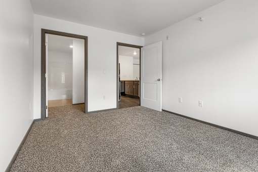 A room with carpeted floor and two open doors.