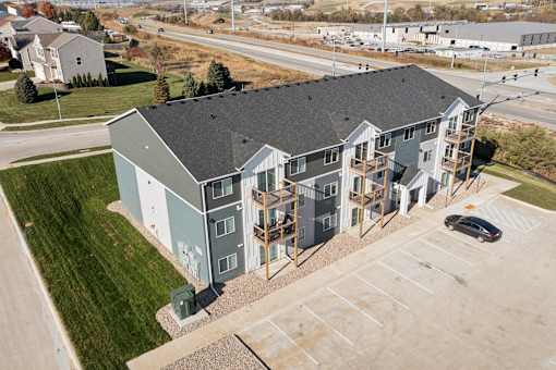 A modern apartment building with a parking lot in front.
