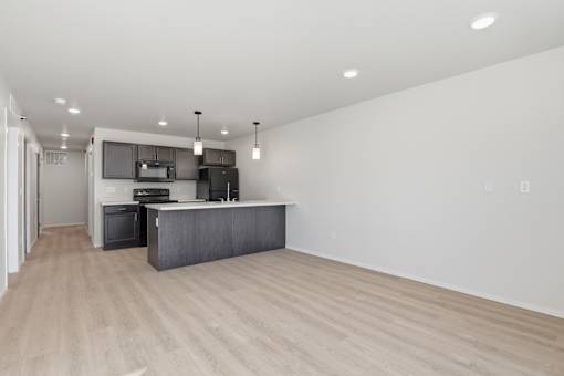 A modern kitchen with a wooden floor and white walls.