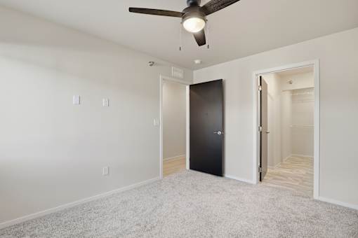A room with a ceiling fan and a black door.