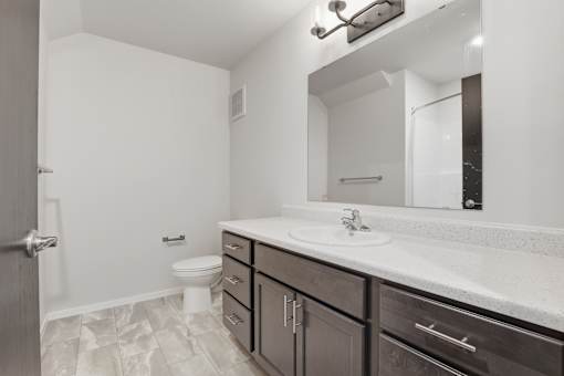A bathroom with a toilet, sink, and mirror.