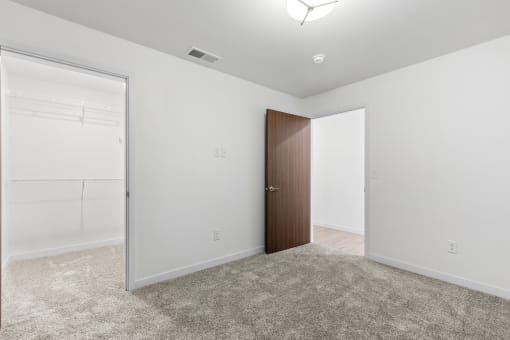 an empty bedroom with white walls and a door to a closet