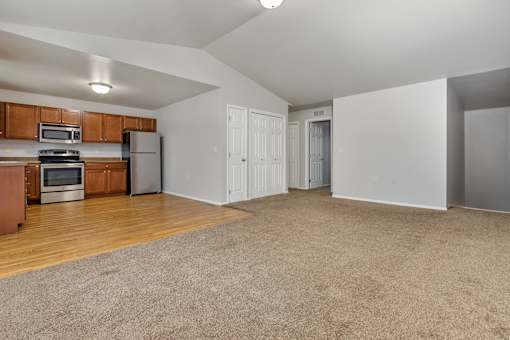 A spacious living room with a kitchen area in the background.