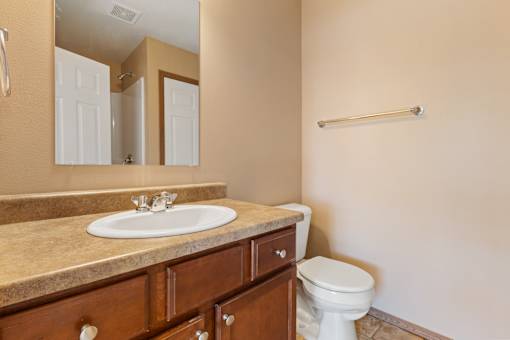 A bathroom with a sink, toilet and mirror.
