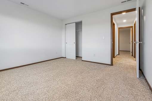 A carpeted room with a door on the left and another door on the right.