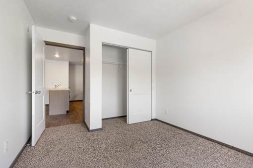A carpeted room with a white door and a mirror.