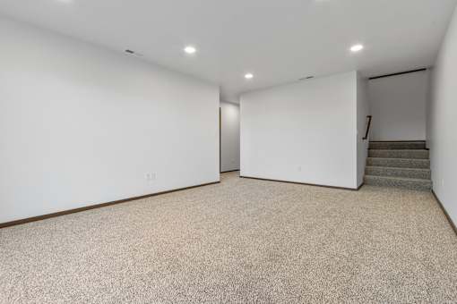 A spacious room with a staircase leading to another room.