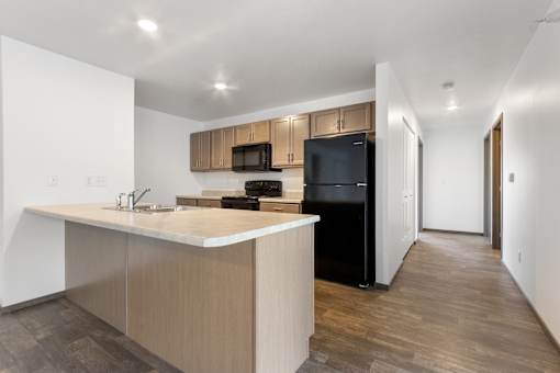 A kitchen with a black refrigerator and wooden cabinets.