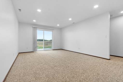 A large empty room with a carpeted floor and a window.