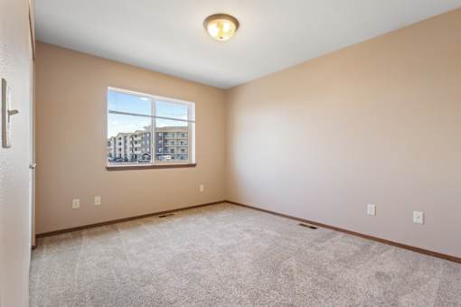 A room with a window showing a view of buildings outside.