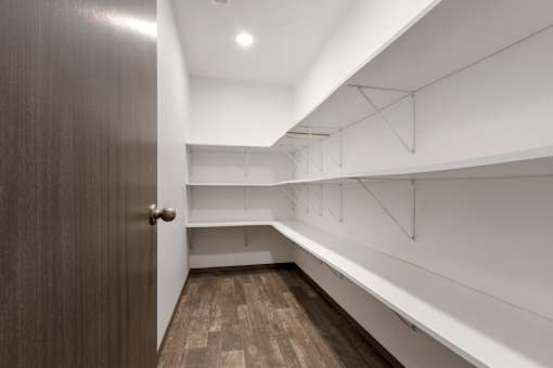 A hallway with a brown door and white walls.