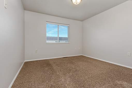 A room with a carpeted floor and a window.