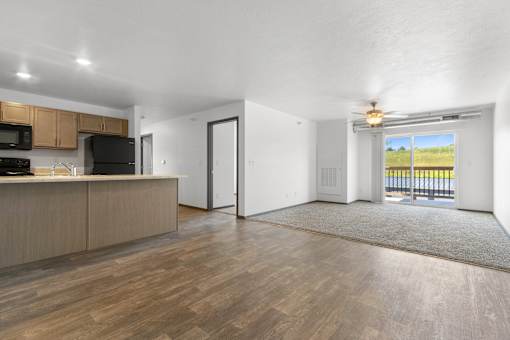 A spacious living room with a kitchen area and a view of the outdoors.
