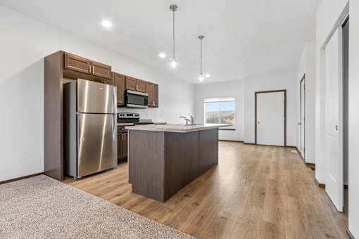 A modern kitchen with wooden floors and stainless steel appliances.
