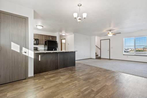 A spacious living room with a kitchen area in the background.