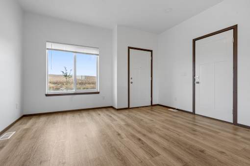 A room with wooden flooring and a window showing a field.