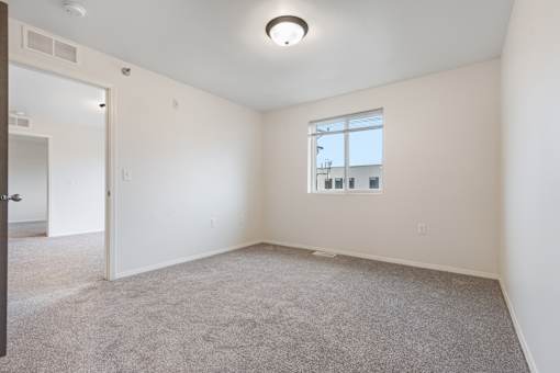 A room with a carpeted floor and a window.