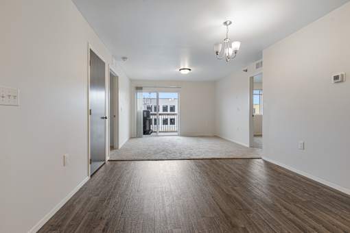 A spacious room with wooden floors and a chandelier.