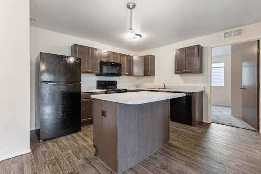 A kitchen with a black refrigerator, microwave, and stove top oven.
