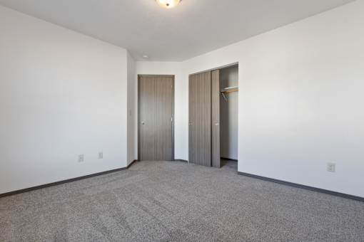 A room with a carpeted floor and two doors.