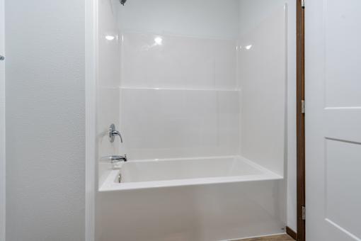 A white bathroom with a tub and a sink.