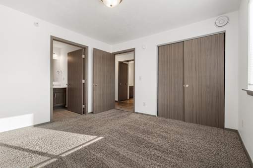 A room with a carpeted floor and three doors.