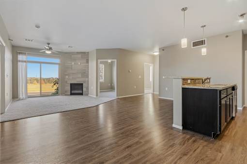 A spacious living room with a fireplace and a kitchen area with a countertop and cabinets.