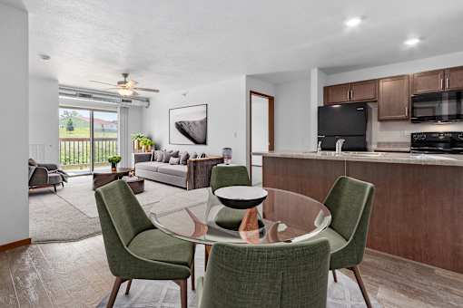 A modern dining room with a glass table and green chairs.