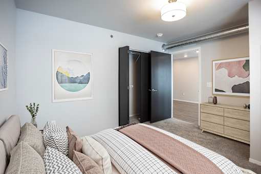 A bedroom with a bed, couch, and artwork on the walls.
