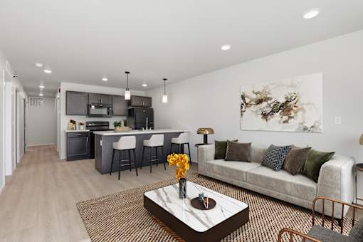 A modern living room with a kitchen in the background.