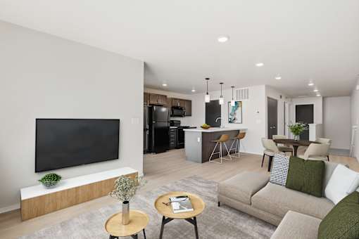 A modern living room with a flat screen TV and a kitchen area in the background.