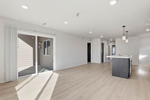 A large, empty room with a sliding glass door leading to a balcony.