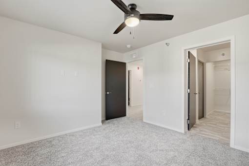 A room with a ceiling fan and two doors.