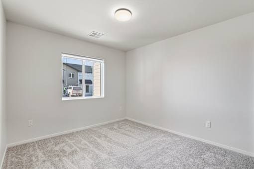 A room with a window showing a view of a building and a car outside.