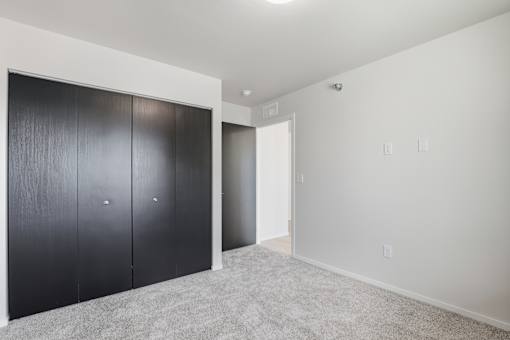 A room with a white wall and a grey carpet.
