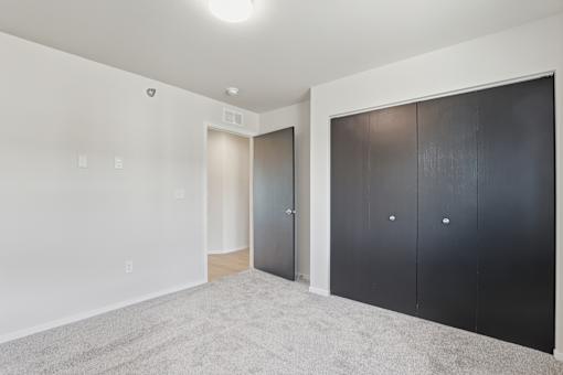 A room with a carpeted floor and two sets of doors.