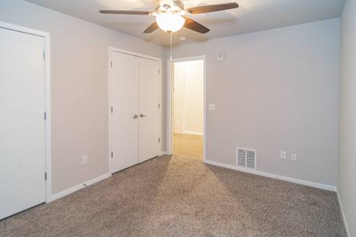 A room with a ceiling fan and carpeted floor.