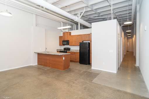 A kitchen area with a black fridge and microwave, a wooden counter, and a white wall.