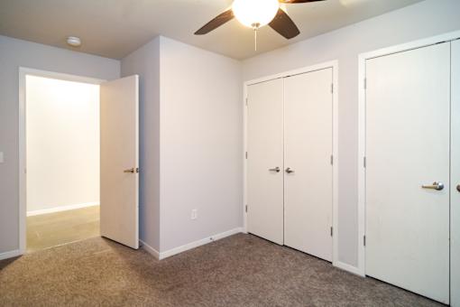 A room with a ceiling fan and three white doors.