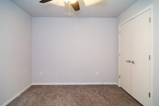 A room with a ceiling fan and a closed door.