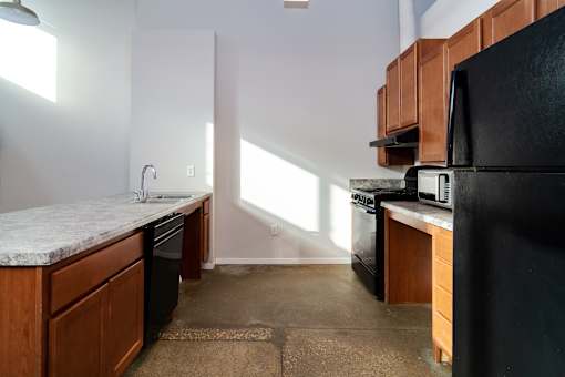 A kitchen with a black refrigerator and wooden cabinets.